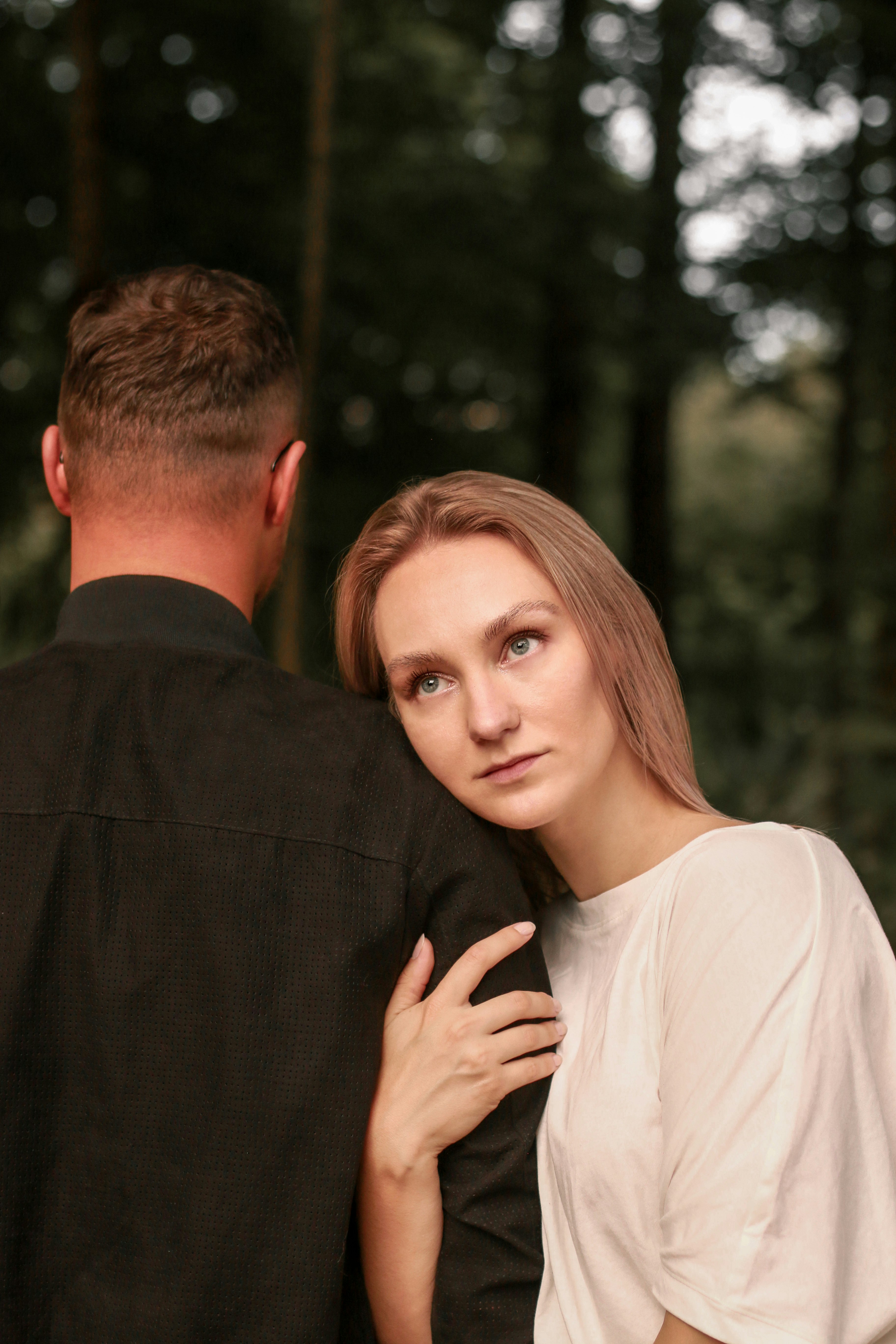 man in black suit jacket hugging woman in white long sleeve shirt